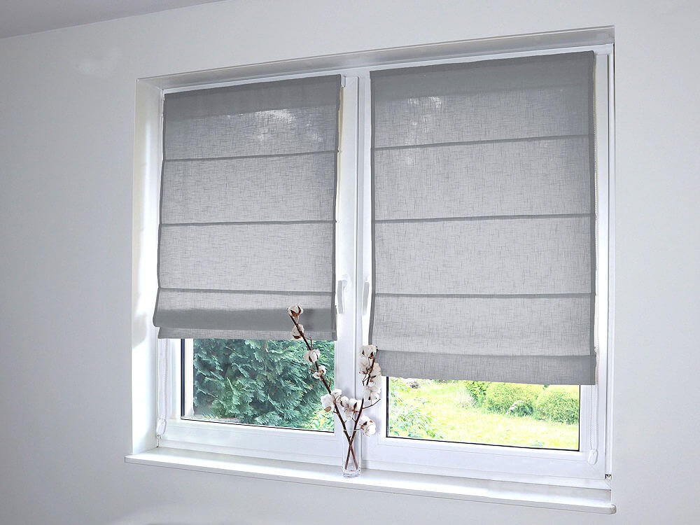 Lniane, jasno-szare rolety rzymskie.